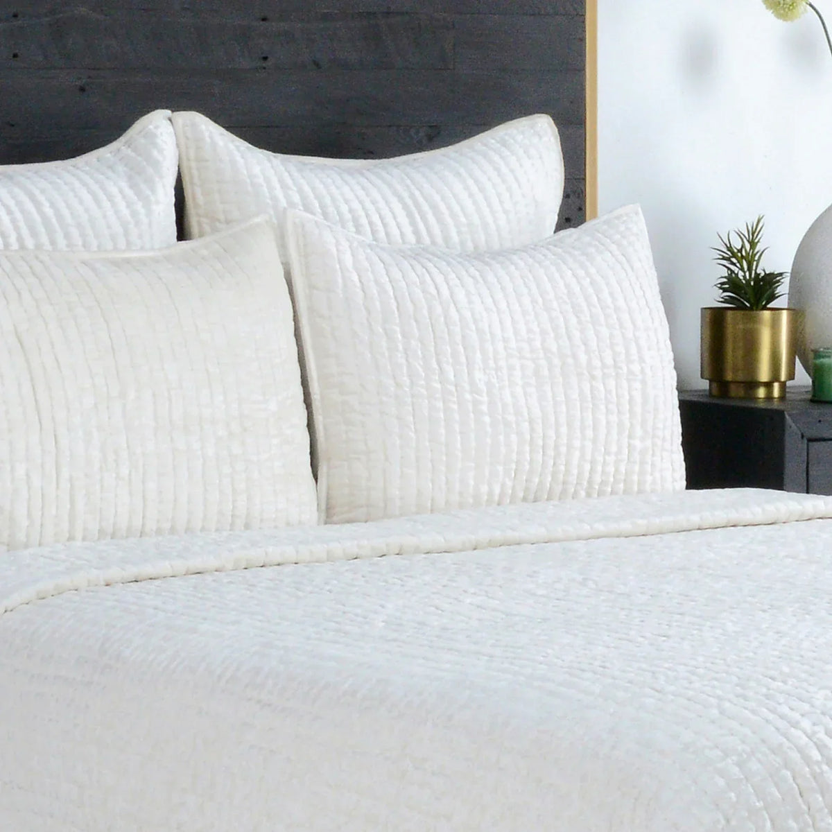 A quilted velvet quilt folded across the foot of a bed