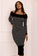 Front view of a black ribbed knit midi dress worn off the shoulder with long sleeves