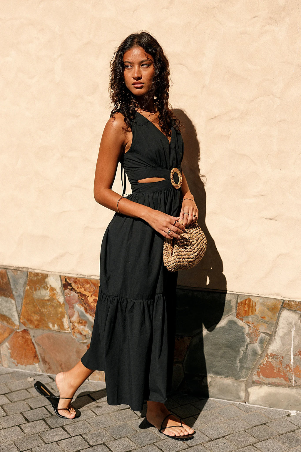 Front view of a black midi dress with a woven round buckle at the front