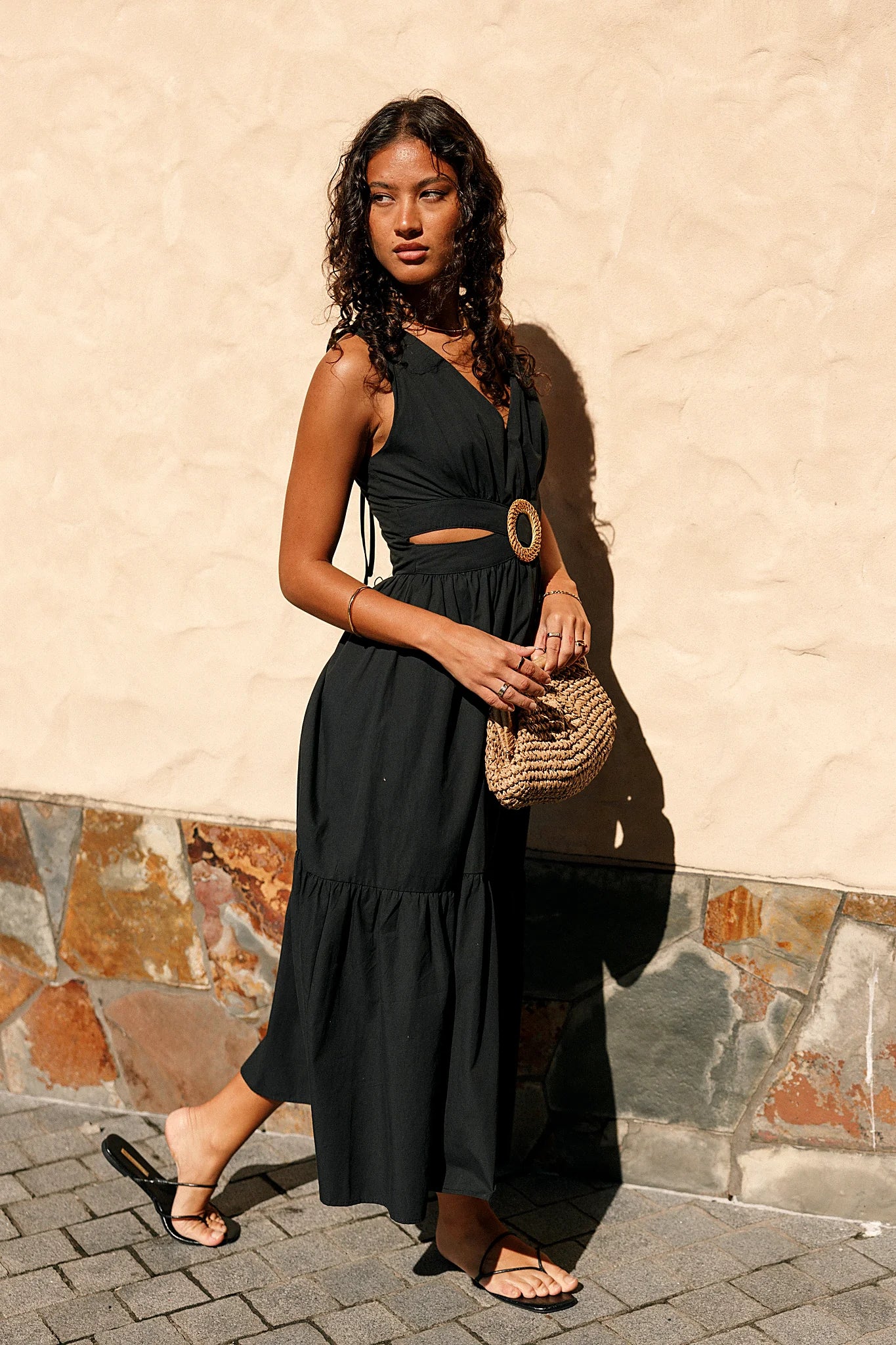Front view of a black midi dress with a woven round buckle at the front