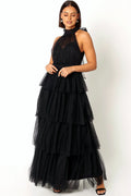 Front view of a black halterneck maxi dress with a tiered tulle skirt