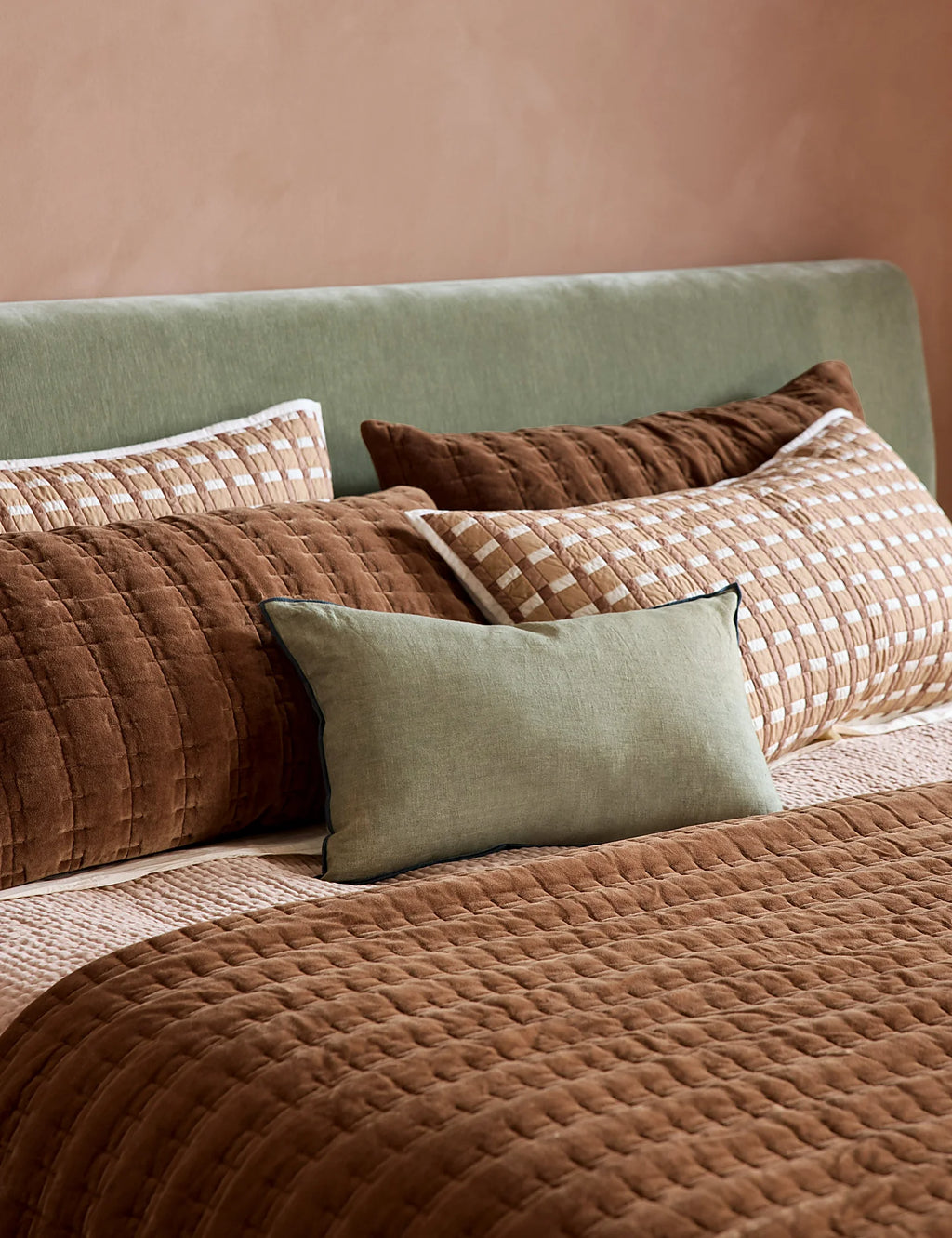 Spring bedding scene with gingham quilted shams on a made bed