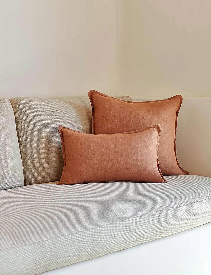 Rust-toned linen lumbar pillow styled in a neutral room