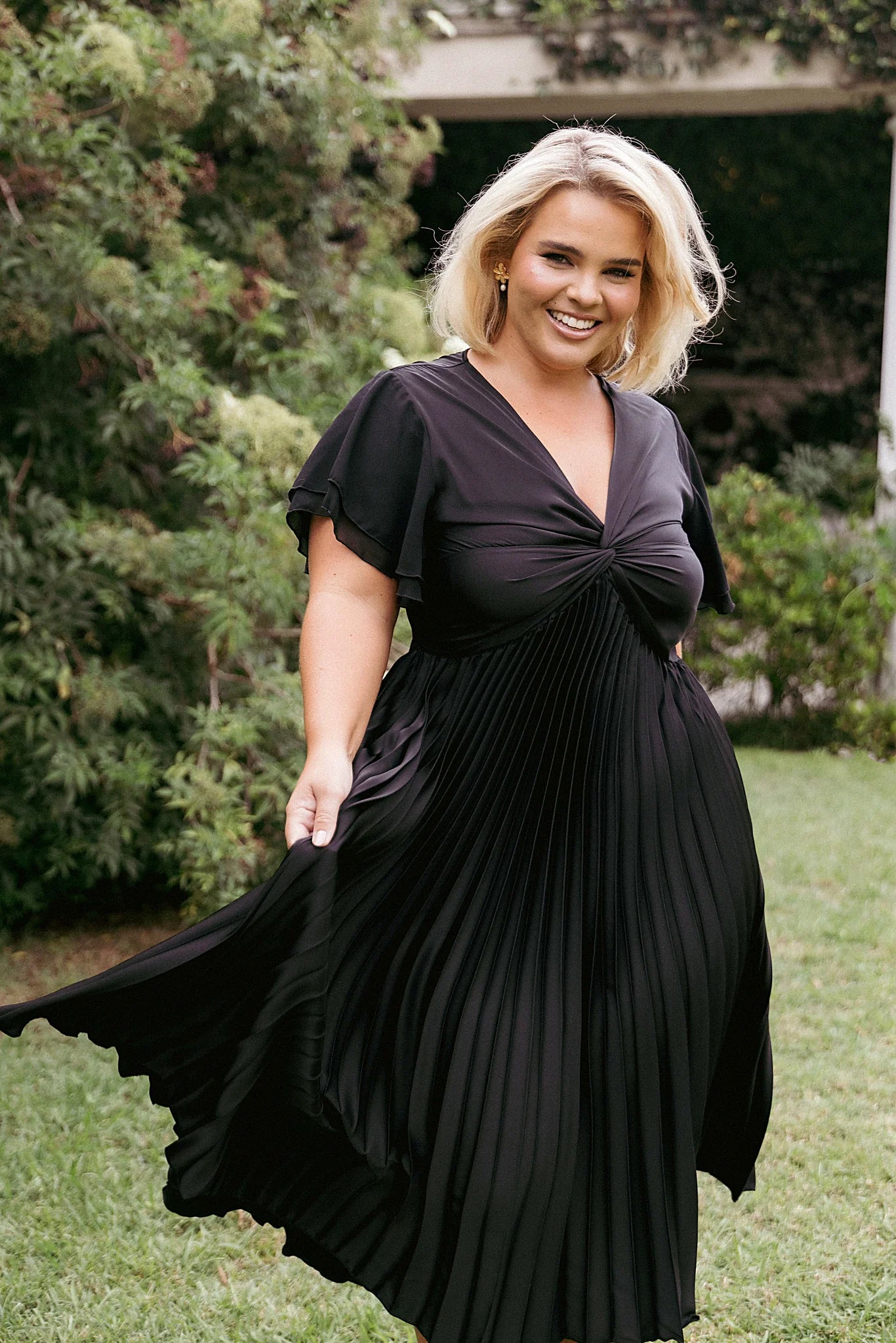 Front view of a black midi dress with flutter sleeves and a V neckline