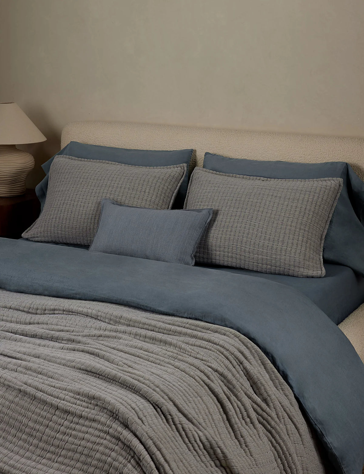 Dusty blue quilted cotton sham in standard size on a made bed