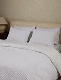 White textured cotton sham shown alongside the blanket