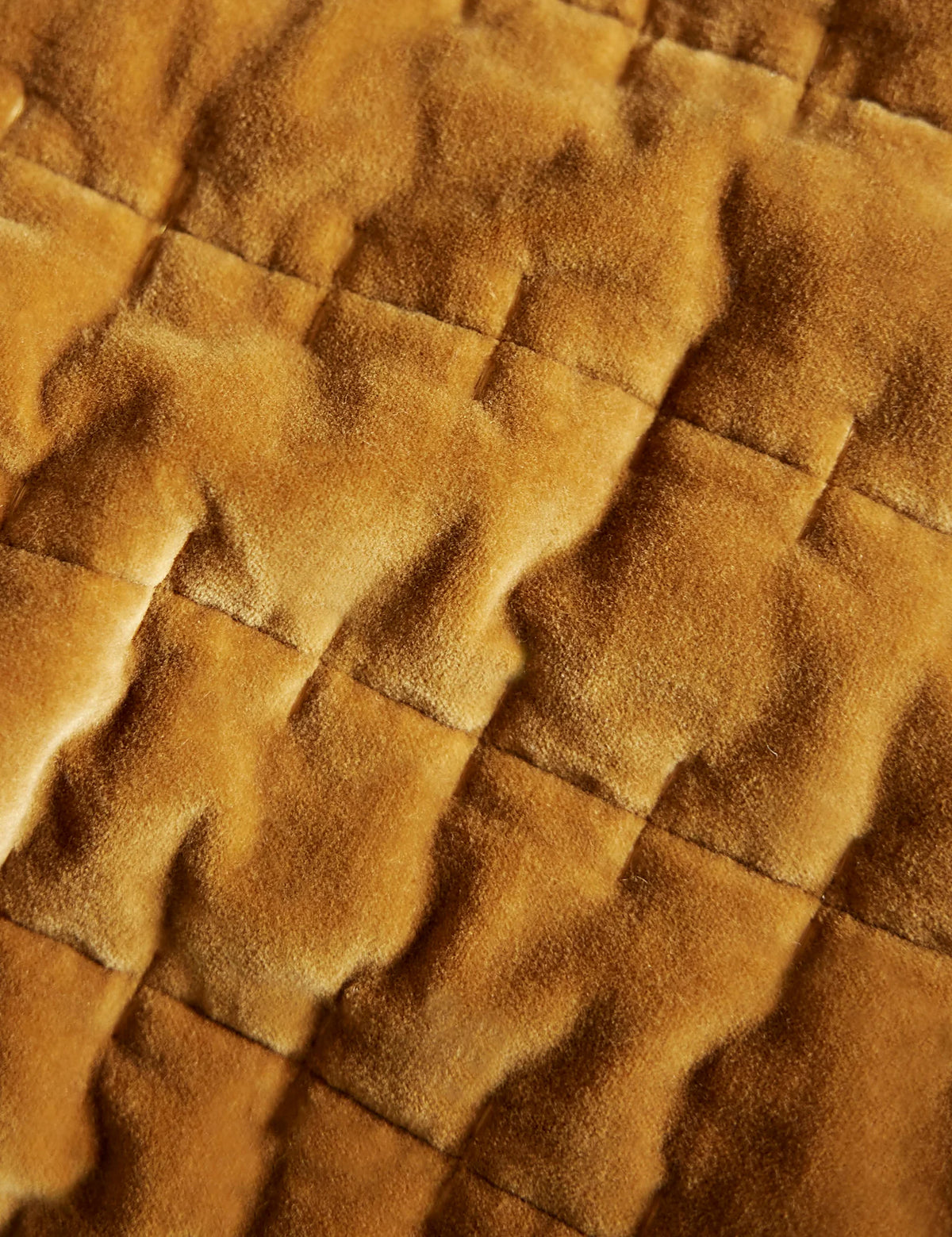 Second view of a marigold velvet quilt folded back at the foot