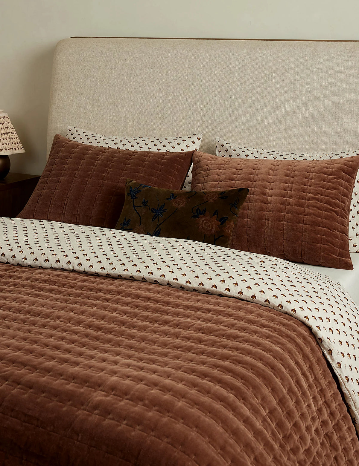 Velvet quilt layered with a quilted sham at the head of the bed